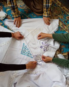 Händer som håller fram broderier från Afghanistan.