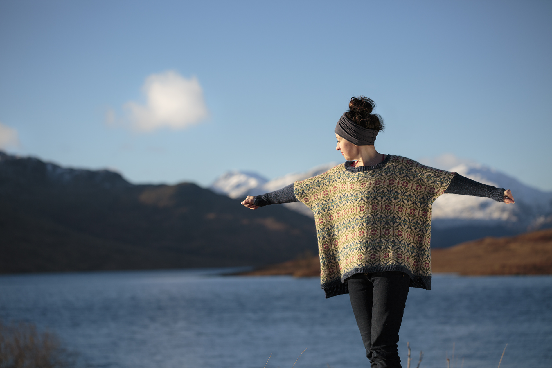 kvinna med stickad jumper med sjö och fjäll i bakgrunden