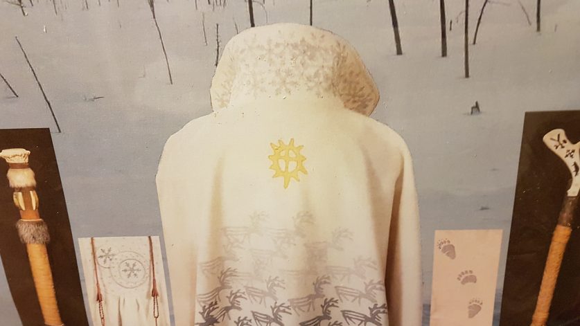 Ryggen på en vintervit cape med grå renar och gul sol.