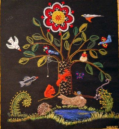 Broderat träd med ekorrar och fåglar i. Nedanför trädet en broderad damm med en kanin och en igelkott.