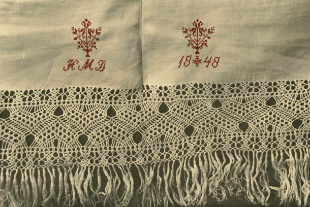 Närbild på flätade fransar med emblemet HMD och daterad 1848.