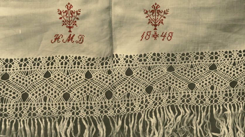 Närbild på flätade fransar med emblemet HMD och daterad 1848.