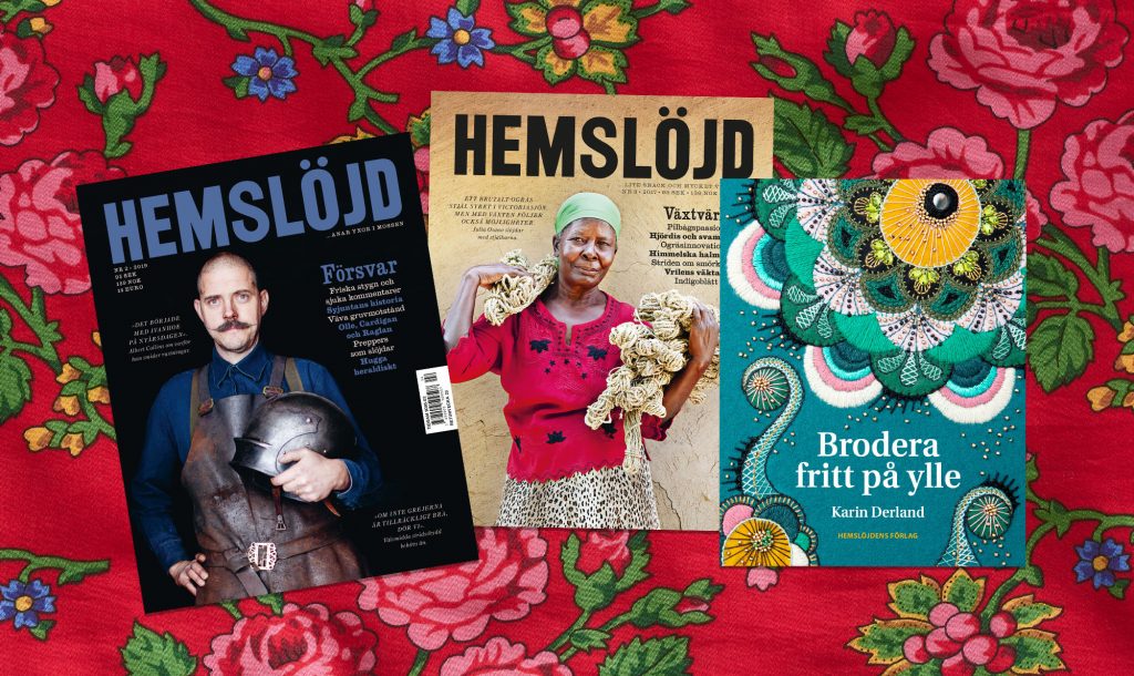 Två utgåvor av tidningen Hemslöjd och boken "Brodera på Ylle" på blommig duk.