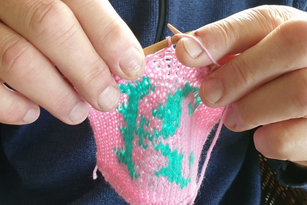 händer som håller i en mönsterstickning