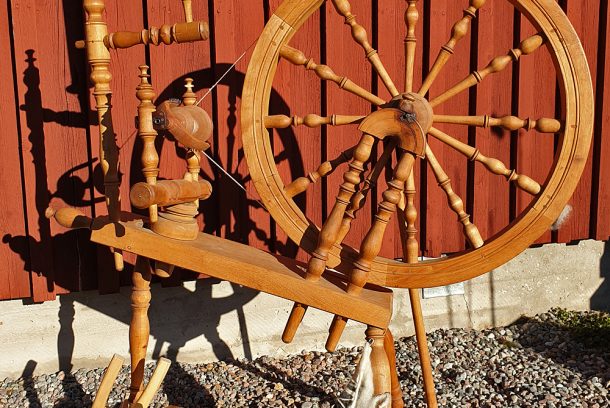 spinnrock och kardor framför en faluröd trävägg