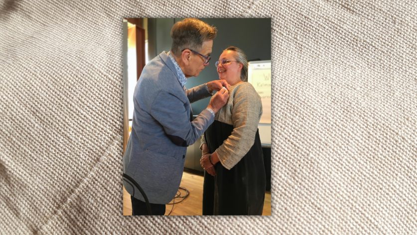 Håkan Liby i blå kavaj fäster silvermedalj på leende Marie Ekstedt Bjersings tröja.