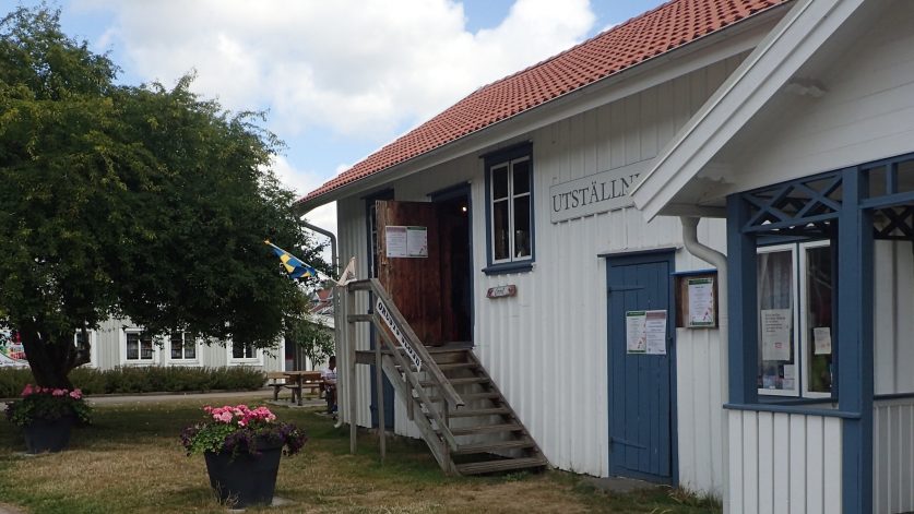 Karins Hus, vitt trå hus med blå knutar, utvändig trappa upp till entrédörr.